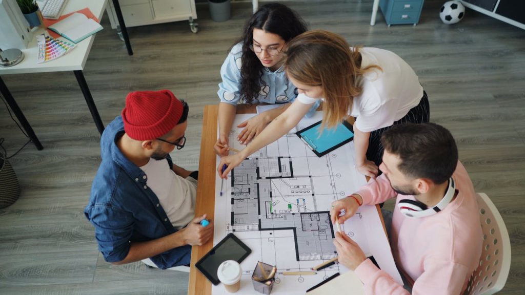Young creative professionals discussing an architectural blueprint in a modern office setting.